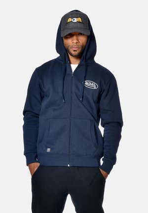 Hoodie zippé bleu marine en mélange de coton doux, avec un patch logo, des poches avant et une capuche réglable avec cordon.
