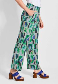 Lichte, gestreepte broek in groen, blauw en zwart met een elastische tailleband en zijzakken; gecombineerd met blauwe hoge hakken.