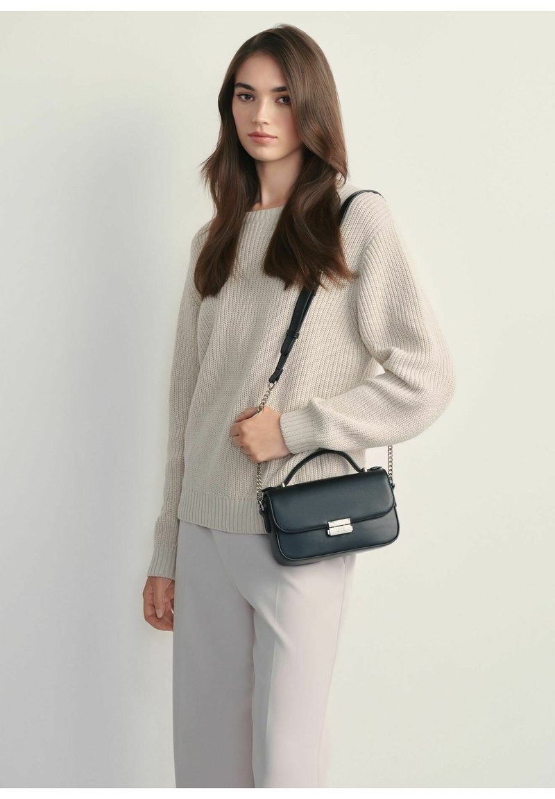 Czarna skórzana torebka na ramię z górnym uchwytem i łańcuszkiem, o prostokątnym kształcie i metalowym zapięciem z przodu, umieszczona na neutralnym tle.