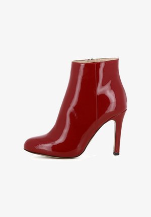 Rote lackierte Ankle Boots mit spitzer Zehenpartie, schlankem Stiletto-Absatz und glatter Textur. Mit seitlichem Reißverschluss für einfaches An- und Ausziehen.