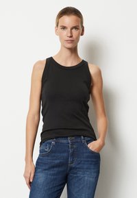 Top negru fără mâneci, cu un decolteu rotund, purtat împreună cu blugi albaștri. Topul are un design ajustat și o textură netedă din bumbac.