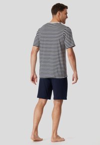 Striped short-sleeve t-shirt in navy and cream, paired with navy shorts. The fabric appears soft with a relaxed fit, suitable for casual wear.
