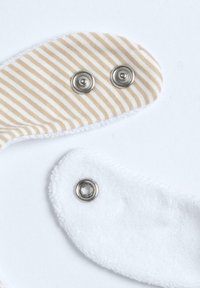 Striped beige and white fabric with snap fasteners; soft textured white material; features two distinct shapes and contrast in patterns.
