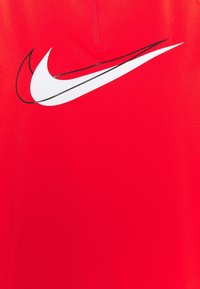 Röd atletisk tröja med en stor vit Nike swoosh-logotyp med svart kontur, tillverkad av mjukt, lättviktigt material.
