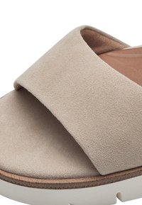 Sandale à glissière en suède beige avec une large sangle supérieure douce et une semelle intérieure rembourrée, dotée d'une semelle en caoutchouc blanche avec un bord texturé.