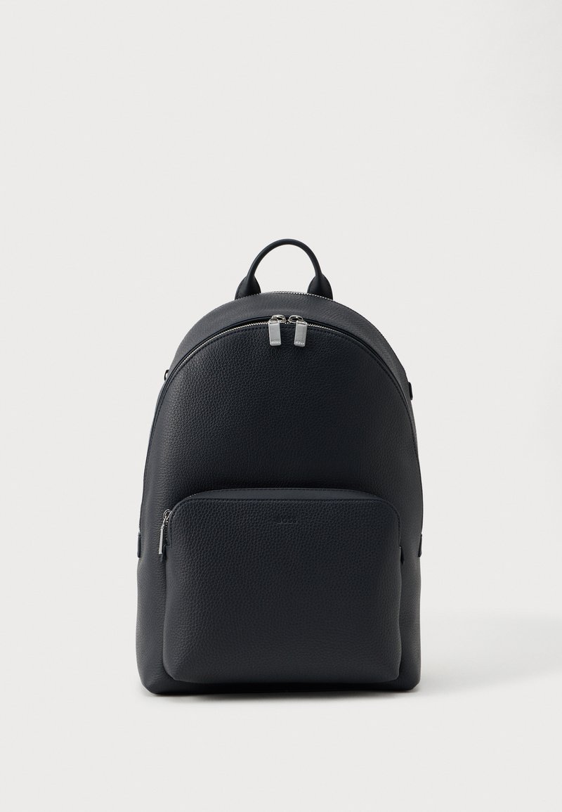 Juodas tekstūruotas odinis kuprinė su dviem užtrauktukais ir viršutine rankena ant paprasto balto fono.