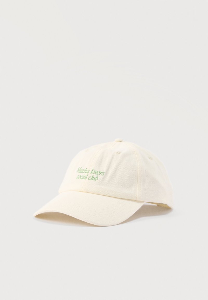 Casquette de baseball blanc cassé à visière incurvée avec texte vert brodé "Matcha lovers social club" sur le panneau avant.
