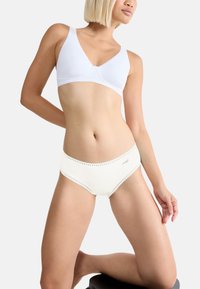 Soutien-gorge bianco in cotone con design liscio e spalline larghe, abbinato a mutandine color crema con bordo in pizzo e un piccolo logo.