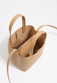 Borsa a tote in pelle color cuoio con doppie maniglie, apertura superiore e tasca interna con zip. Texture liscia e design minimalista.