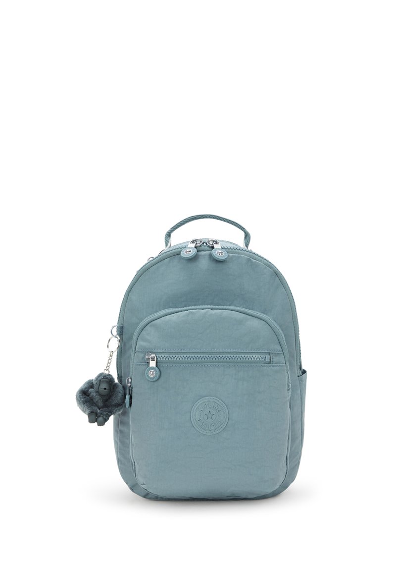 Piccolo zaino azzurro chiaro con tasca anteriore con zip, manico superiore e portachiavi a forma di scimmia in peluche appeso alla zip laterale.