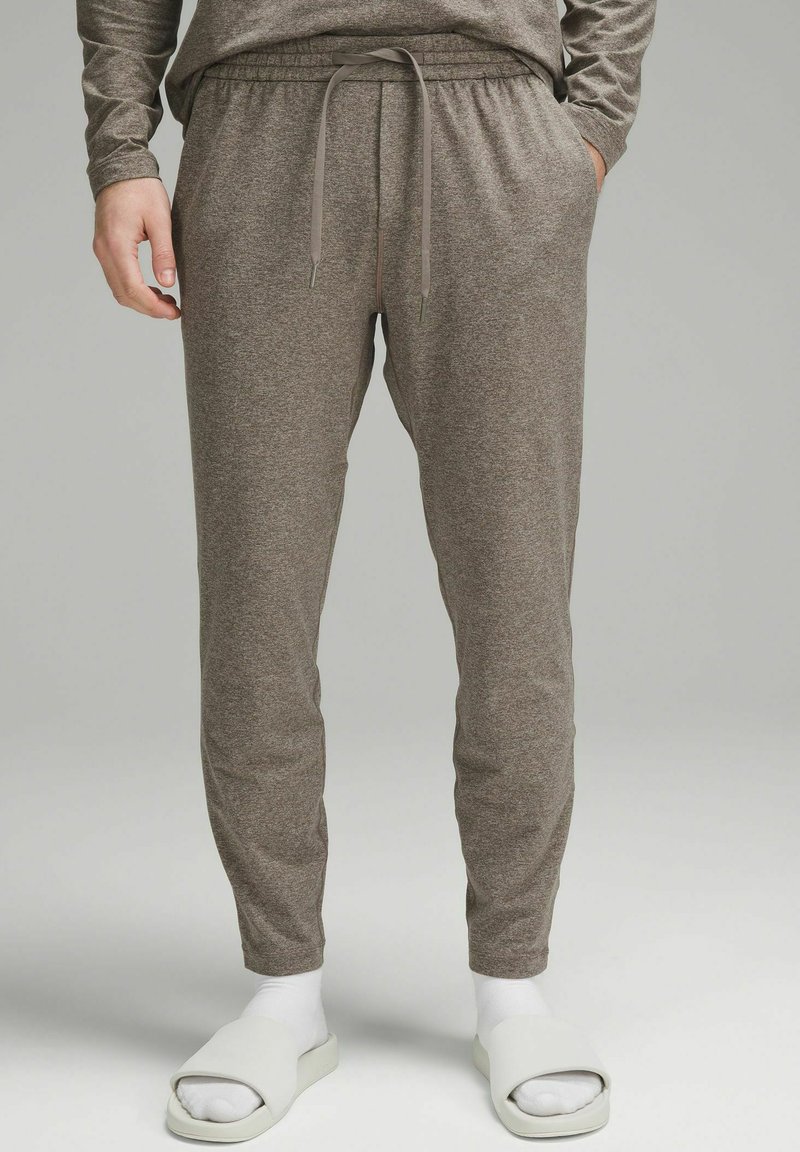 Slim-fit, keskikohaline joggers heledast pruunist kangast, elastse vöökohtadega, nööriga, küljetaskudega ja ribadega mansettidega.