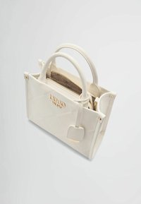 Sac à main blanc matelassé avec deux poignées courtes, accents en matériel doré et un compartiment zippé à l'intérieur. Présente le logo sur le devant.