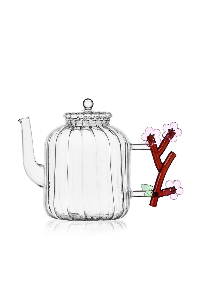 Szklany czajnik z pionowym żebrowanym wzorem, przezroczysty, okrągłą pokrywką oraz uchwytem w kształcie gałązki z różowymi kwiatami i zielonymi liśćmi.