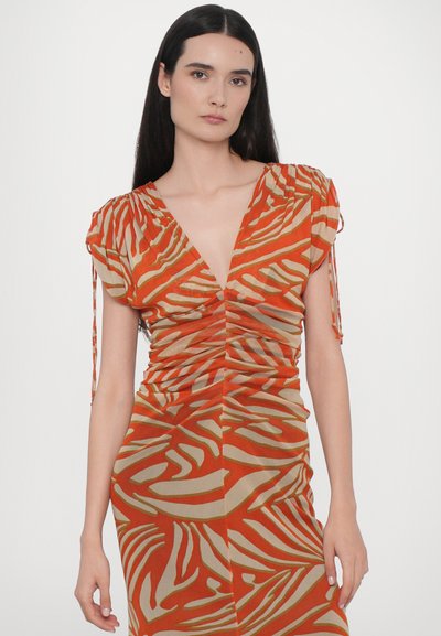 Rynkad klänning i orange med beige zebramönster, med korta puffärmar och djup V-ringning. Lätt, mjukt tyg med flytande textur.