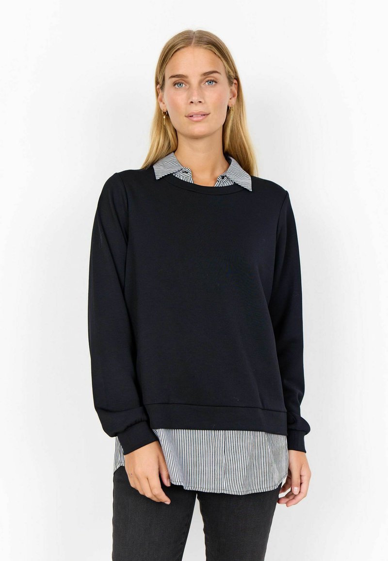 Schwarzer Kapuzenpullover, der über ein schwarz-weiß gestreiftes Hemd mit Kragen geschichtet ist. Hat lange Ärmel und eine lockere Passform. Sanfte Textur, lässiges Design.