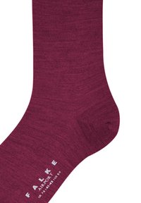 Viininpunainen sukka hienosta neuloksesta. Siinä on sileä pinta ja vahvistettu kärki, sivussa painettu brändi- ja kokotiedot.