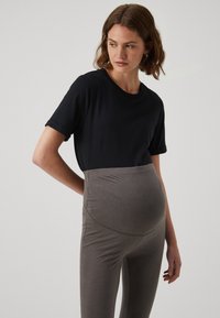 Top preto de mangas curtas combinado com leggings cinzentas de cintura alta, projetadas para uso na maternidade, com tecido elástico e uma textura suave.