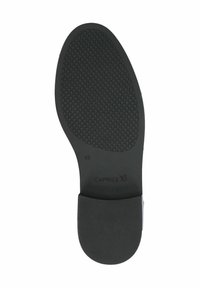 Soletta in gomma nera con un motivo di impugnatura testurizzato, con un'area del tallone liscia e un marchio che recita "CAPRICE."