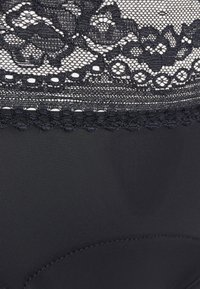 Black lace fabric at the top, intricate floral patterns, transition to solid black material below, finished with a scalloped lace trim.