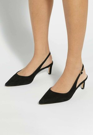 Black suede slingback heels with a pointed toe and a low block heel, featuring a cutout design and an adjustable strap with a gold accent.