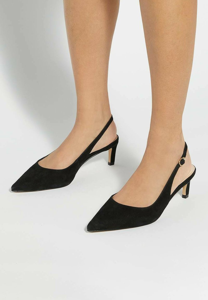 Black suede slingback heels with a pointed toe and a low block heel, featuring a cutout design and an adjustable strap with a gold accent.