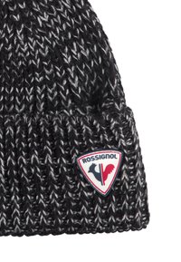 Berretto lavorato a maglia bianco e nero con risvolto, caratterizzato da un patch con il logo Rossignol nei colori rosso, nero e bianco.
