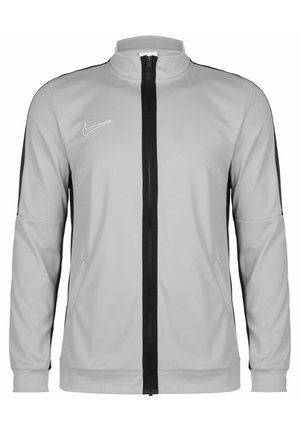 Hellgraue Nike-Sportjacke mit durchgehendem schwarzem Reißverschluss, schwarzen Seitenstreifen, zwei Fronttaschen und langen Ärmeln.