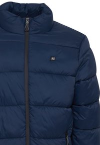 Mørkeblå puffer-jakke med høj krave, vandret quiltet design, lynlås foran og lille logo på brystet. Blødt, isoleret materiale.