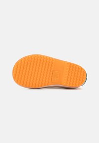 A cipő talpának orange színű, texturált gumi alapja van, barázdált mintával a tapadás érdekében, valamint sima bézs szélén. Az oldalon feltüntetett méret.