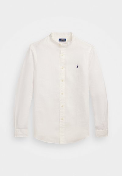 Λευκό πουκάμισο από λινό με μακριά μανίκια, γιακά με ταινία και κίτρινια κουμπιά. Διαθέτει ένα μικρό ναυτικό λογότυπο στο αριστερό στήθος.