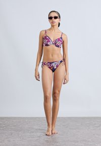 Bikini multicolore avec un motif floral, haut de type soutien-gorge à armatures et bas de bikini avec liens réglables sur les côtés. Tissu lisse avec une sensation légère.