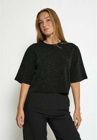 Juodas trumpas rankovės viršus su tekstūruotu bangų raštu. Pagamintas iš minkštos medžiagos, su atviru kaklu ir laisvu siluetu.