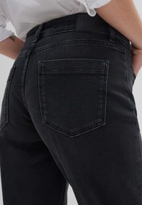 Mustat farkut, joissa on sileä pinta, kaksi takataskua ja vyötärötagi. Kangas on hieman joustavaa mukavuuden vuoksi.