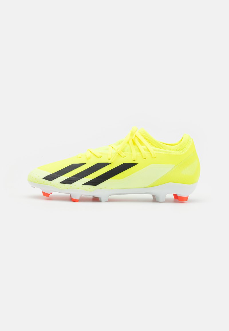 Crampons de football jaunes avec des rayures noires, dessus synthétique, surface texturée et semelle blanche avec des accents rouges au niveau du talon et des crampons.