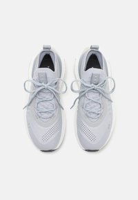 Light grey athletic shoes feature a knit upper, textured accents, round laces, and a white midsole. Includes a logo on the tongue.