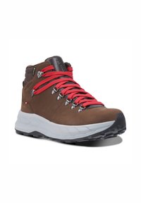 Scarpa da trekking in pelle marrone con lacci rossi, occhielli argentati e una suola intermedia grigia e testurizzata. Dotata di una suola in gomma per una migliore aderenza.