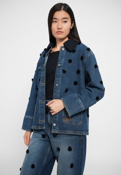 Jeans jakna s črnimi cvetličnimi aplikacijami, standardni ovratnik in gumbno zapiranje, v kompletu z ujemajočimi se jeans hlačami. Modra barva, teksturirana.