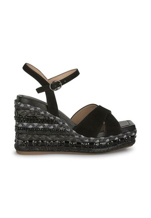 Black suede wedge sandal with a platform. Features crisscross straps and an ankle strap with a buckle. The wedge has braided texture and beaded accents.
