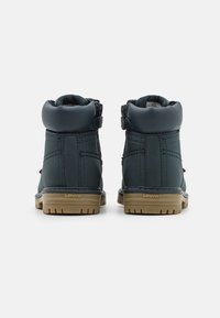 Tmavě modré kožené boty s polstrovaným límcem, dvojitými zipy a texturovanou hnědou gumovou podrážkou se síním logem Levi's.