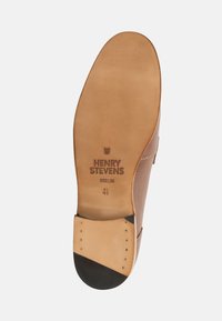 Leder-Schuhsohle in hellbrauner Farbe mit glatter Textur, ausgestattet mit einer schwarzen Zehenkappe. Sichtbares gestempeltes Logo "HENRY STEVENS BERLIN".