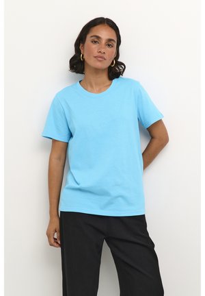 Hellblaues Baumwoll-T-Shirt mit kurzen Ärmeln, einem runden Ausschnitt und einem lockeren Schnitt, kombiniert mit schwarzen Hosen. Glatte Textur, einfarbig.