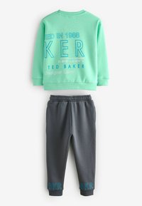Ljusgrön sweatshirt med fet blå text och grå sweatpants med blå accenter vid fållen. Mjukt tyg, avslappnad passform, bekväm design.