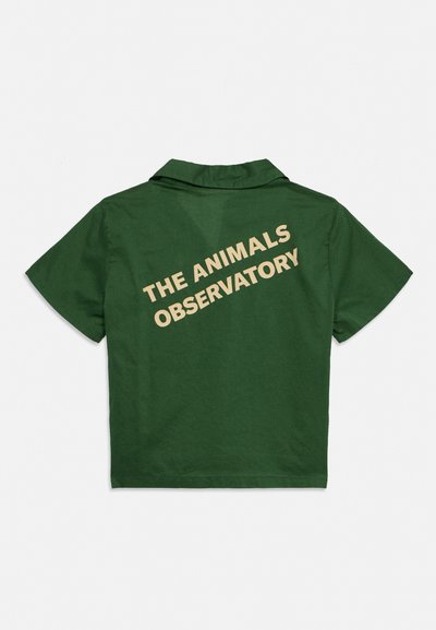 Тъмнозелена риза с къс ръкав с яка и бежов текст с надпис "THE ANIMALS OBSERVATORY" диагонално на гърба.