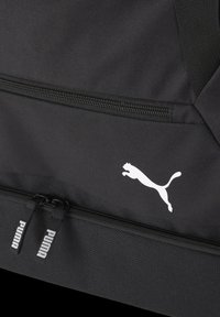 Black backpack with a textured fabric, featuring a white Puma logo, dual zipper closures with "PUMA" branding on the zipper pulls.