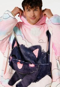 Oversized hoodie gemaakt van zacht, pluizig materiaal; roze met pastelkleurige wolkenpatronen en een illustratie van een zwarte kat. Voorzien van een grote voorkantzak en capuchon.