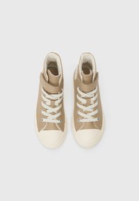 Augstie sporta apavi gaiši brūnā sintētiskā materiālā, ar bežām gumijas purngalu un krēmkrāsas šņorēm. Mīkstais oderējums redzams apkaklē.