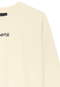Felpa color crema con scollo rotondo e testo in stile graffiti nero "Disclaimer" sulla parte superiore sinistra del petto.