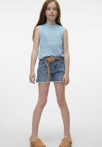 Jasnoniebieski, dzianinowy, bezrękawnik z geometrycznymi wzorami, zestawiony z dżinsowymi szortami i plecionym, brązowym paskiem. Brązowe buty na płaskiej podeszwie.