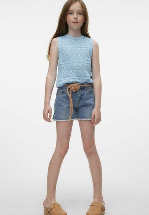 Top senza maniche lavorato a maglia blu chiaro con motivi geometrici, abbinato a pantaloni corti in denim e una cintura intrecciata color carne. Scarpe marroni senza lacci.
