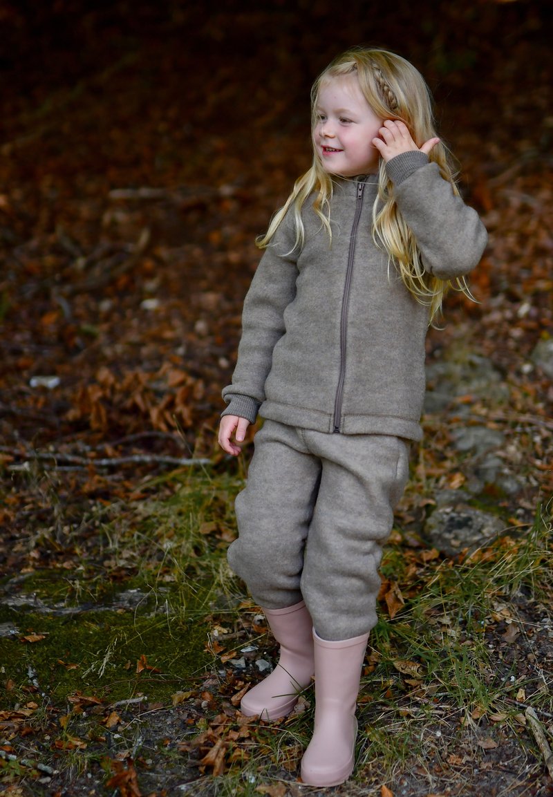 Brun fleecejakke med matchende bukser, begge med lynlåslukning og ribstrikkede manchetter. Pinke gummistøvler fuldender outfittet.